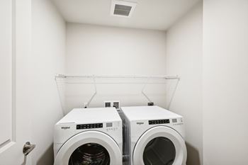 Two white washing machines in a small white room.
